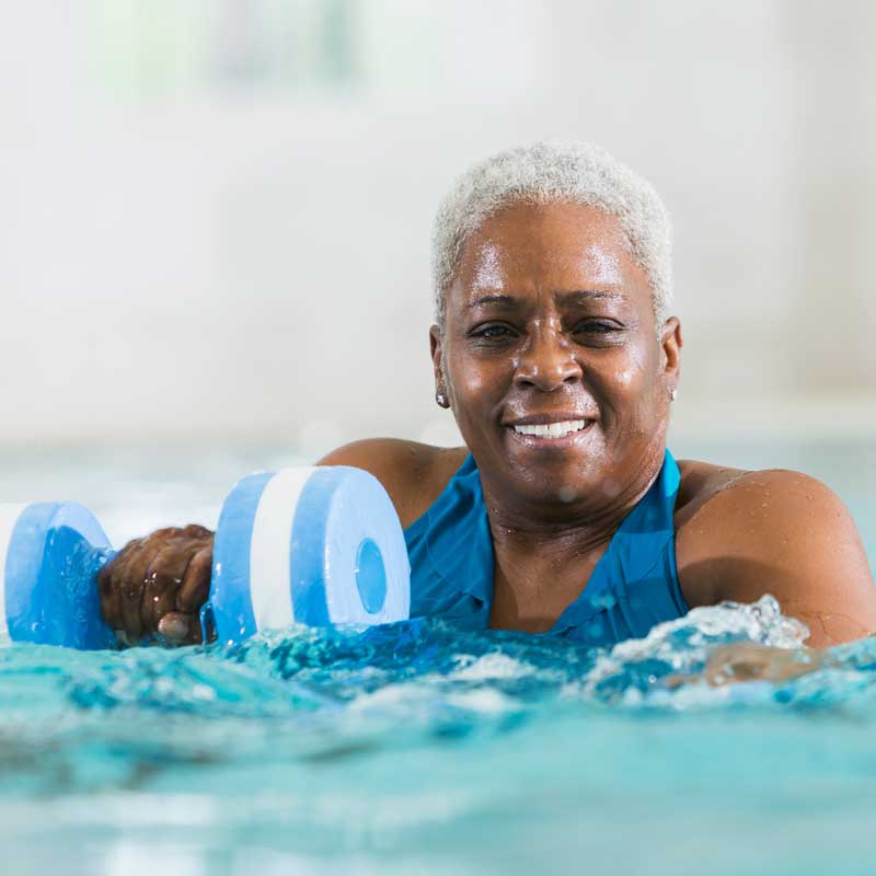 A senior woman uses weights while swimming in a pool